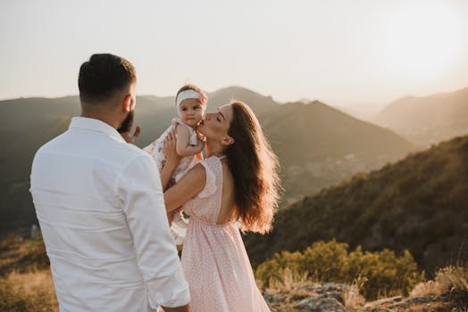 A loving family enjoying a picturesque sunset view from a mountain top during summer.