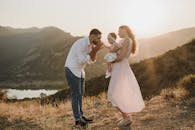 一个快乐的家庭带着婴儿在山上欣赏风景优美的日落