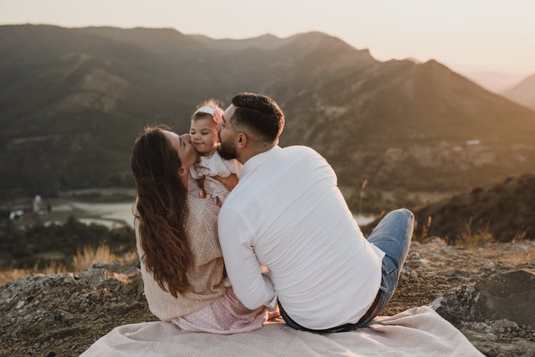 A Mother And Father Kissing The Baby Girl