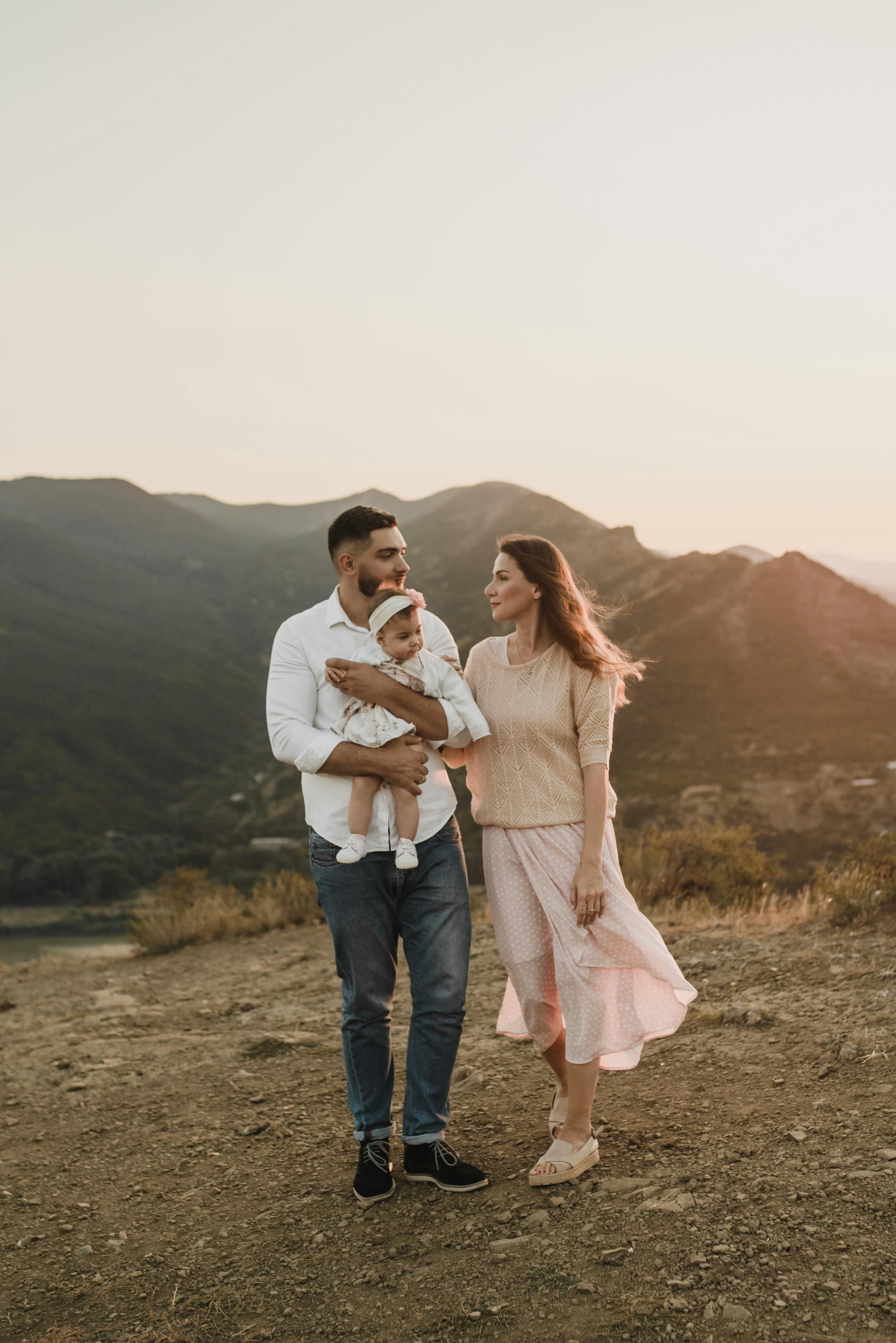 a father carrying a baby girl while looking his wife