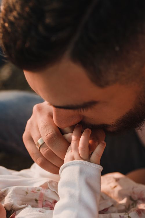 Free A loving father kisses his baby's hand in a close-up outdoor scene. Stock Photo