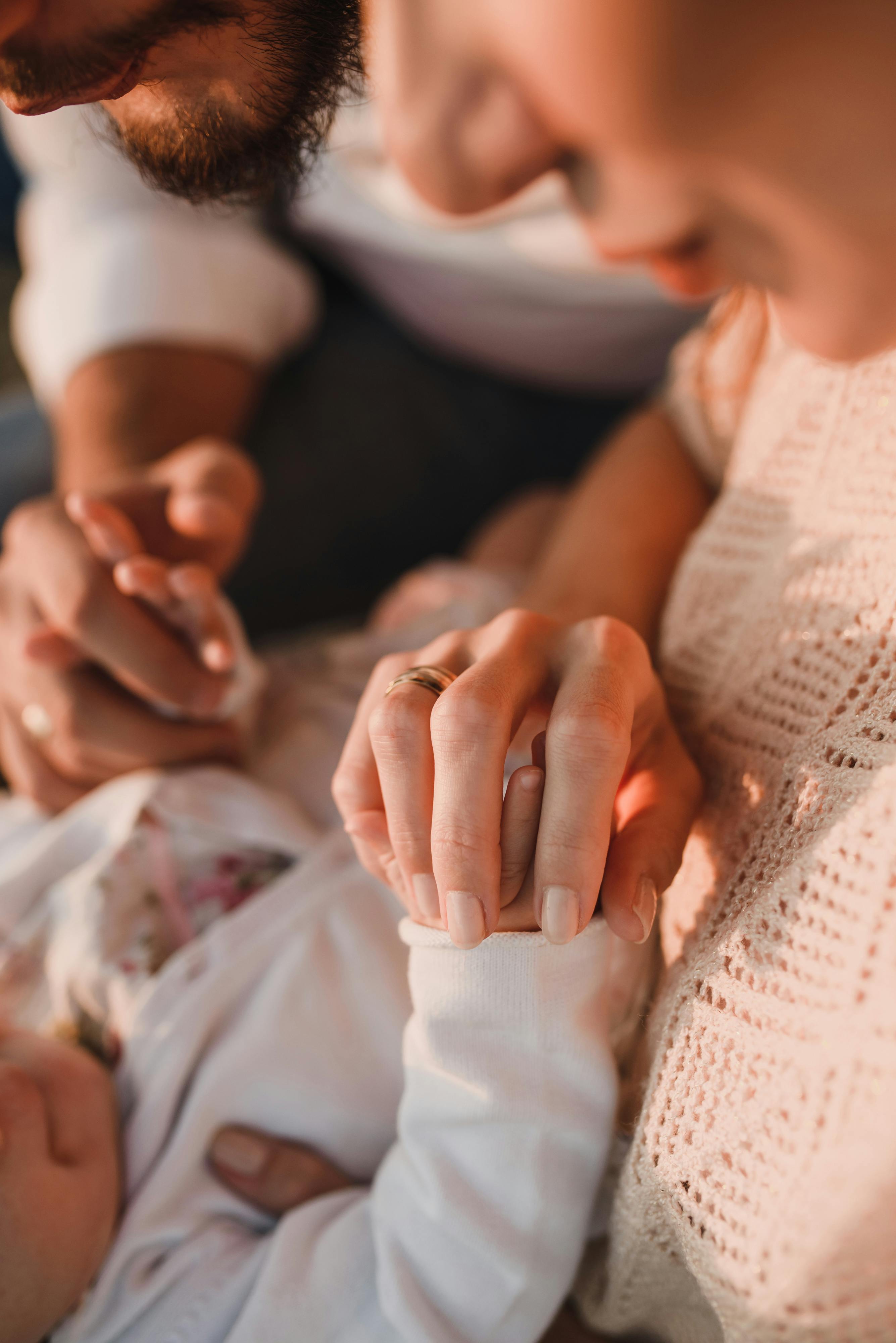 close up of mother and baby holding hands