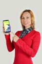 Cheerful woman demonstrating smartphone and looking at camera