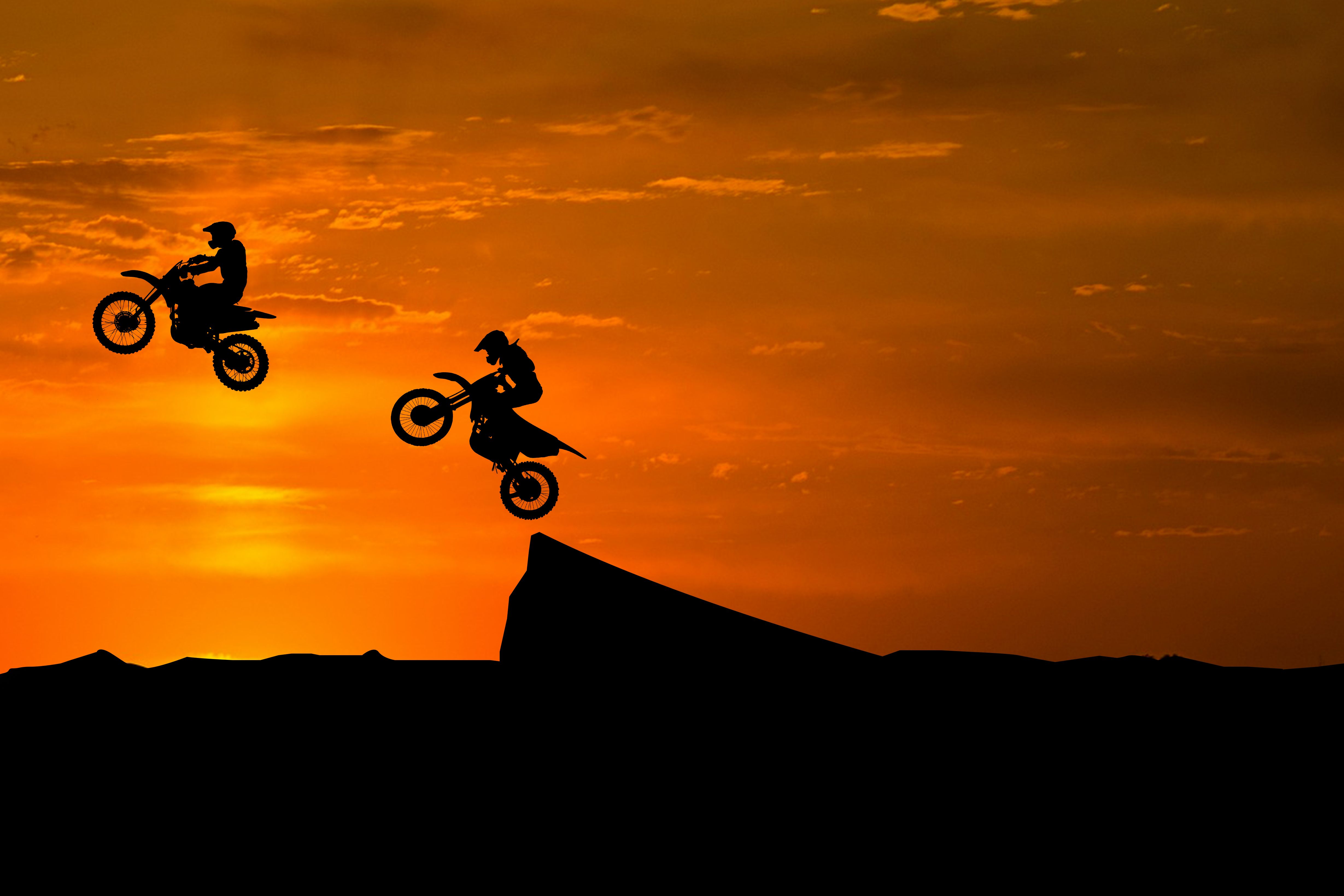 Riders silhouetted against an amber sky. Photo by Shift GraphiX on Pexels.