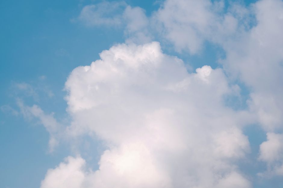 Bright fluffy clouds float serenely in a clear blue sky, creating a calming atmosphere.