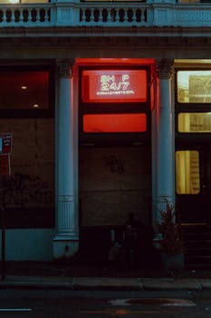 Moody city street with illuminated neon signs at night, capturing a modern urban aesthetic.