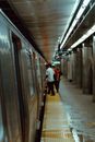 Anonymous passengers taking subway from platform under shiny lamps