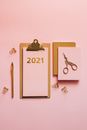 2021年，带有粉红色纸张的金色剪贴板及其配件的顶视图