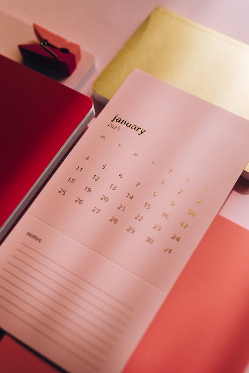 Free From above of stylish notebooks and pink calendar paper with notes on pink background Stock Photo