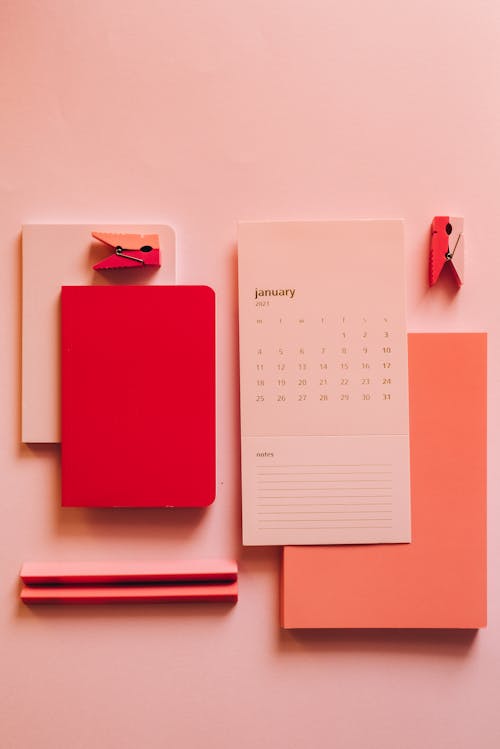 From above minimalistic composition of calendar paper with pink notebooks on pink background
