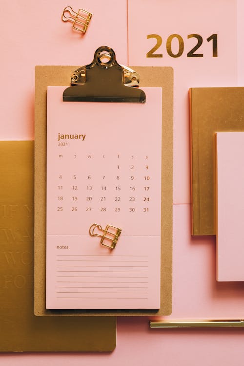 Clipboard with pink calendar on table