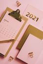 粉色背景上印有2021年日历和办公文具图案，并点缀着金色