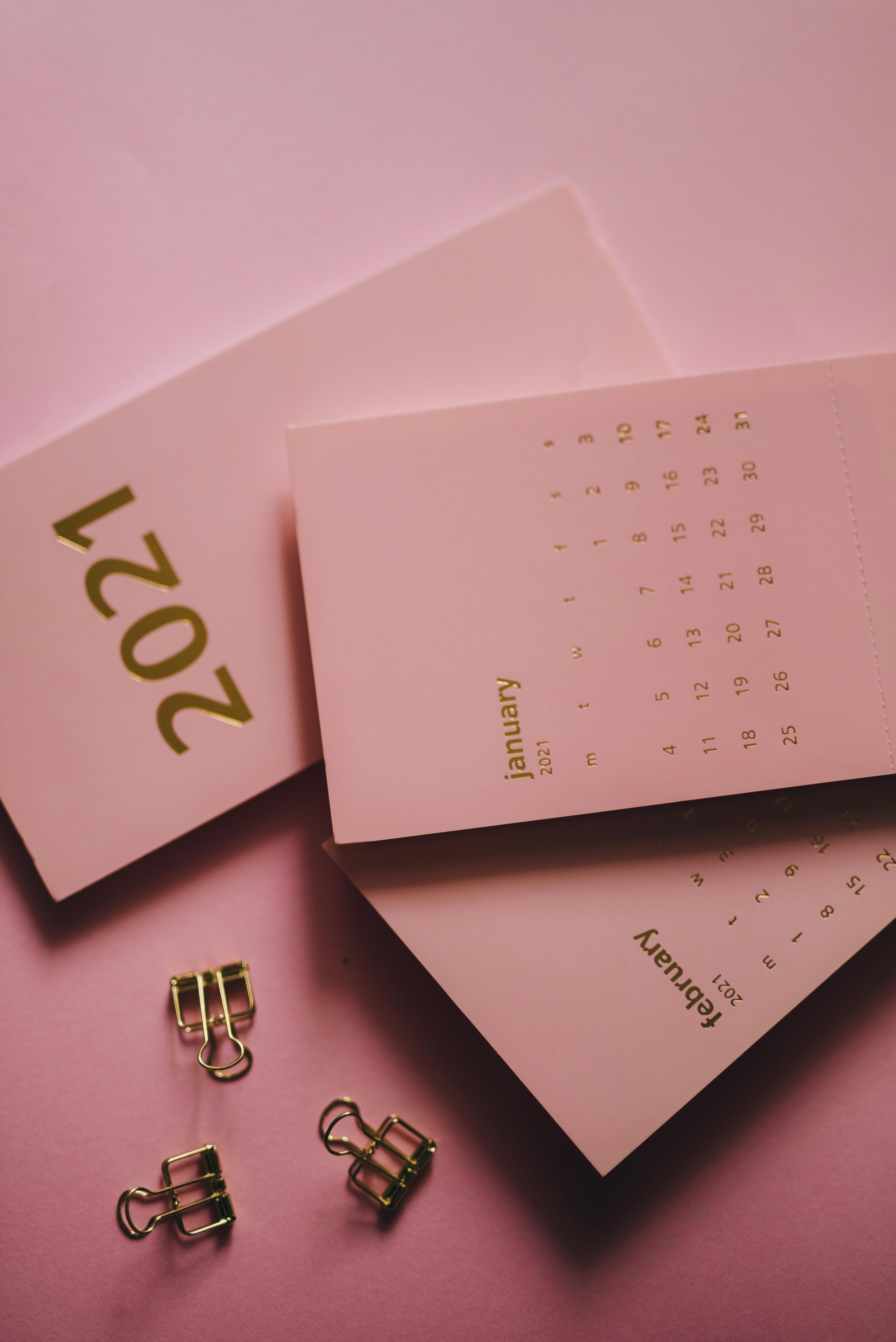 modern calendars near metal clips on pink background