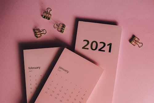 Free Top view of modern paper calendars with numbers and words near metal clips on pink background Stock Photo