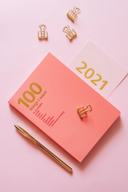 A Pen and a Planner on a Pink Surface