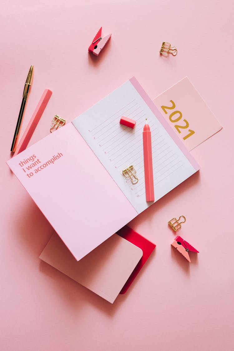 A Pen On An Open Notebook On A Pink Surface