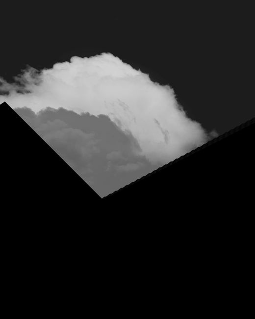 Abstract black and white photo featuring clouds and geometric silhouettes in a dynamic composition.