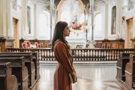 在一座灯光优美、长凳排列整齐的历史悠久教堂里，一名妇女庄严地站立着