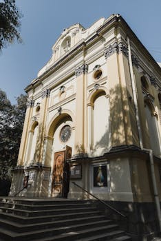 晴朗的天空下，历史悠久的教堂立面显得优雅，台阶通向一个大木箱