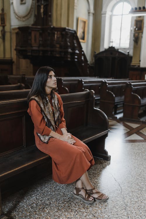 Femme En Robe Orange Debout à Côté D'un Canapé En Cuir Noir