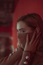 Serious calm female in brown sweater decorated with pearl looking away on blurred background of apartment