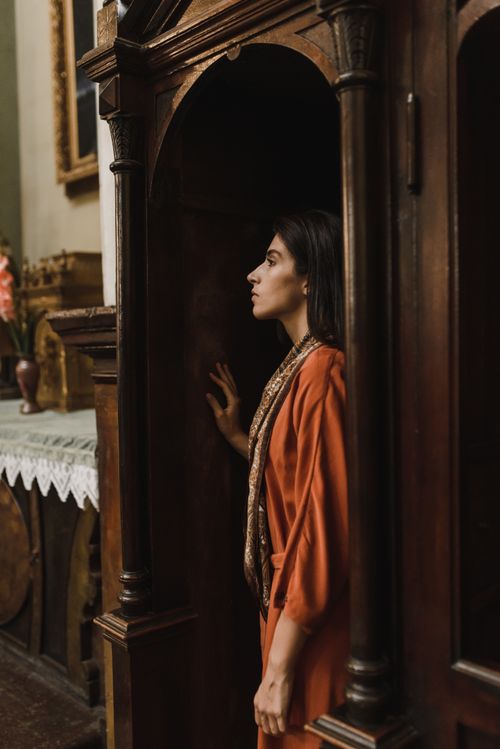 Free A woman standing in a church confessional booth, embracing solemn reflection and faith. Stock Photo