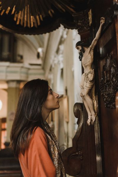 Pessoa orando diante de uma imagem de Jesus Cristo