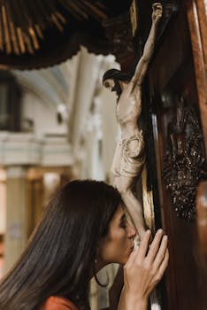 A woman showing devotion by kissing a crucifix inside a church.