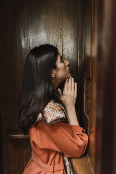 一名妇女在教堂的忏悔室里双手合十祈祷
