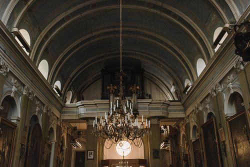 Free Captivating view of a classical church interior highlighting an ornate chandelier and architectural arches. Stock Photo