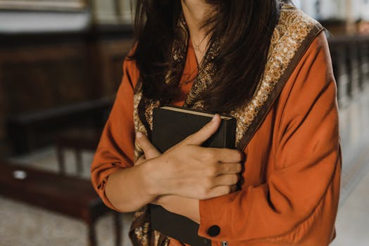 一名妇女在宗教环境中手持一本书的特写，象征着信仰与灵性