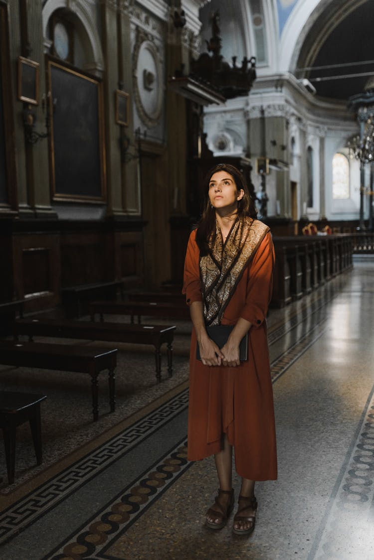 Woman In Orange Dress Standing On Church Aisle