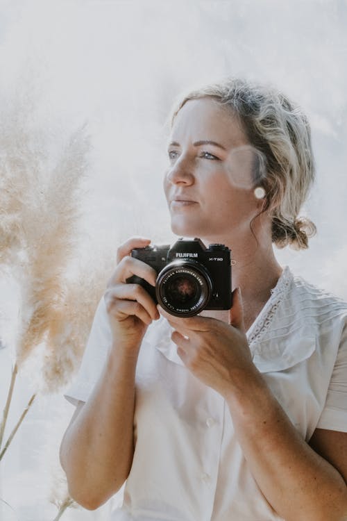 Woman in White Blouse Holding Black Camera