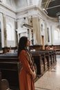 一名妇女在一座历史悠久的教堂内静静伫立，默默冥想，感受着宁静