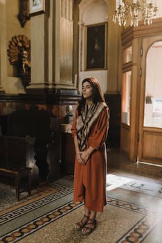 一位身着传统服装的妇女，沐浴在温暖的灯光中，若有所思地站在一座历史悠久的教堂里