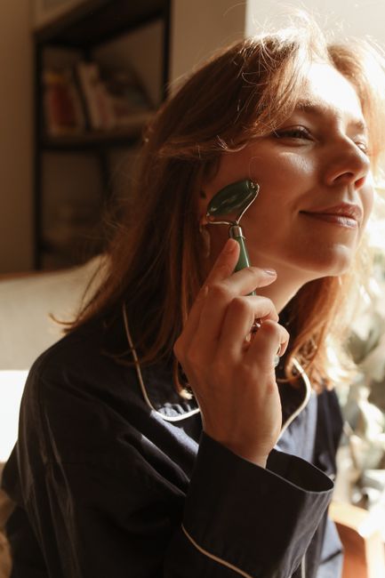 Close-up of a woman using a jade roller for a facial massage, enjoying a relaxing morning ritual.