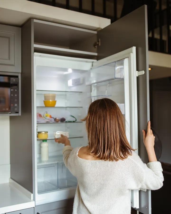 Door Gasket Replacement in La Mesa, CA Woman reaching into a refrigerator with a door seal that needs replacement in La Mesa