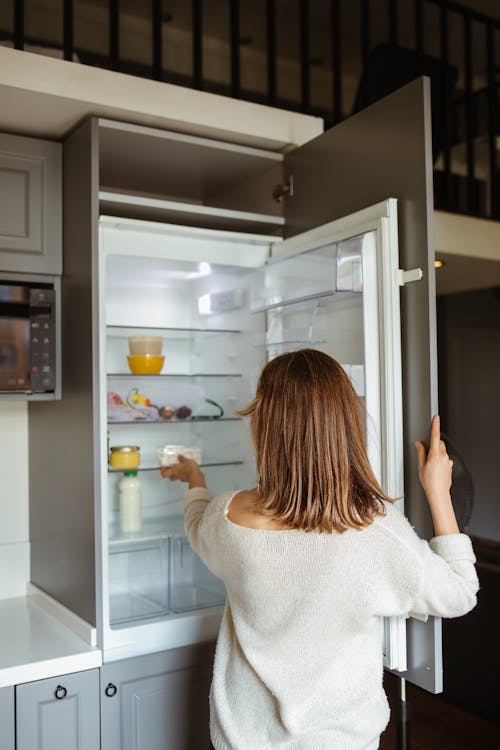 Woman in White Sweater Near Refrigerator