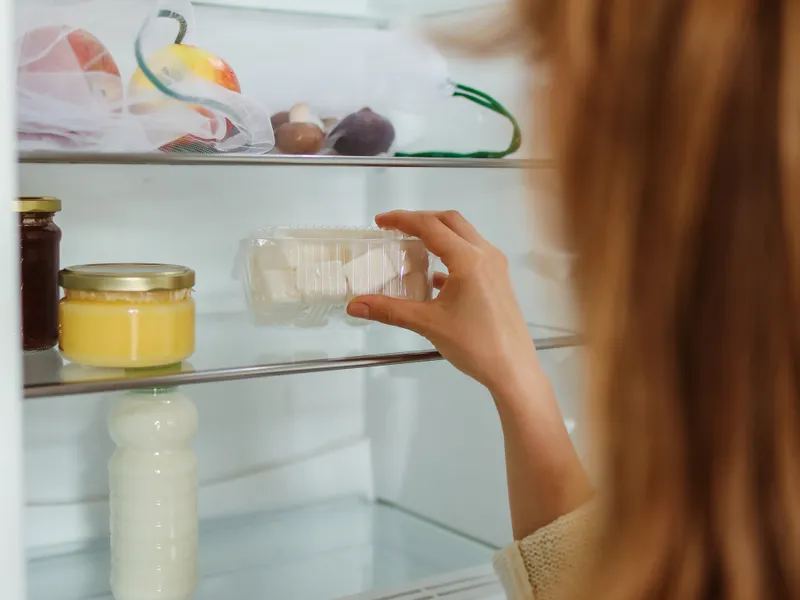Woman organizing refrigerator shelves and reaching for a jar Woman organizing refrigerator shelves and reaching for a jar