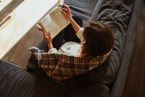 Brunette Woman Reading Book on Sofa