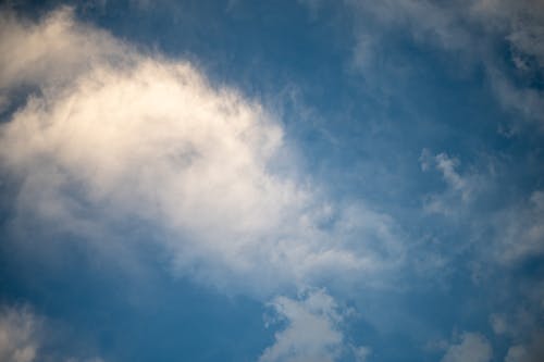 Free Low angle of bright fluffy floating clouds under blue sky at sunny day Stock Photo