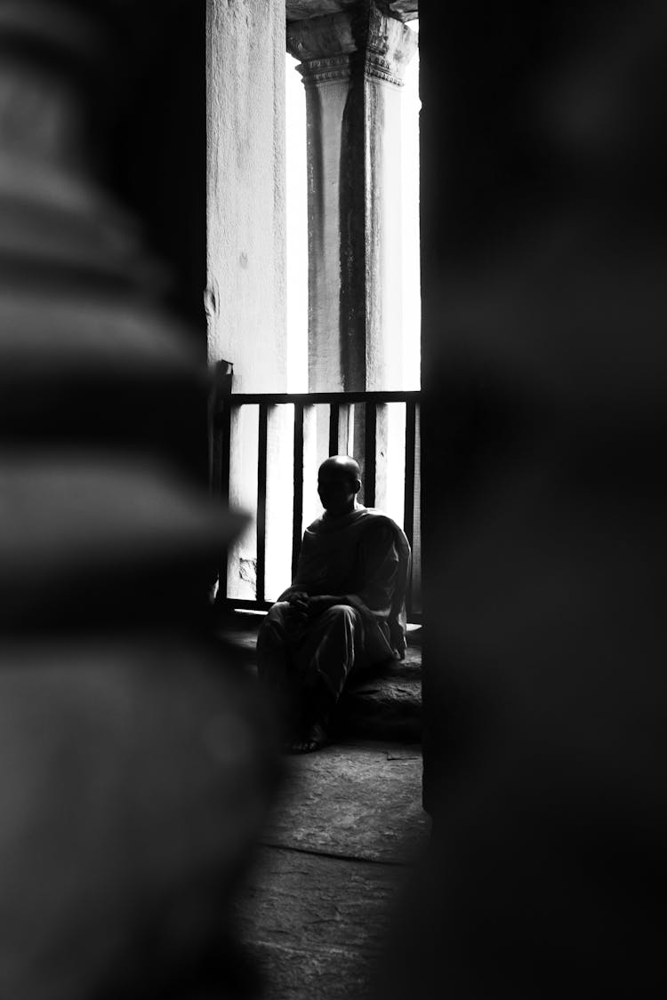 Unrecognizable Monk Sitting On Floor In Temple