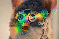 特写镜头中，可爱的蓬松玩具反射出彩色光芒，并配有电子眼