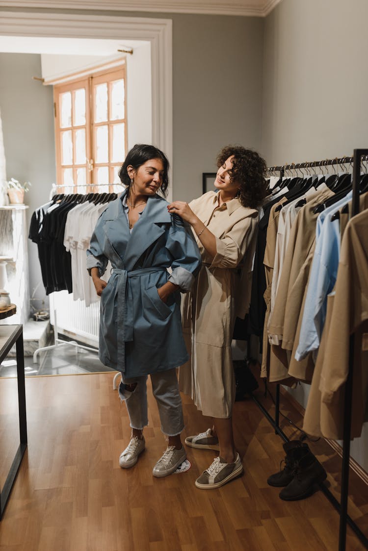 Curly Haired Person Fixing The Woman's Trench Coat 