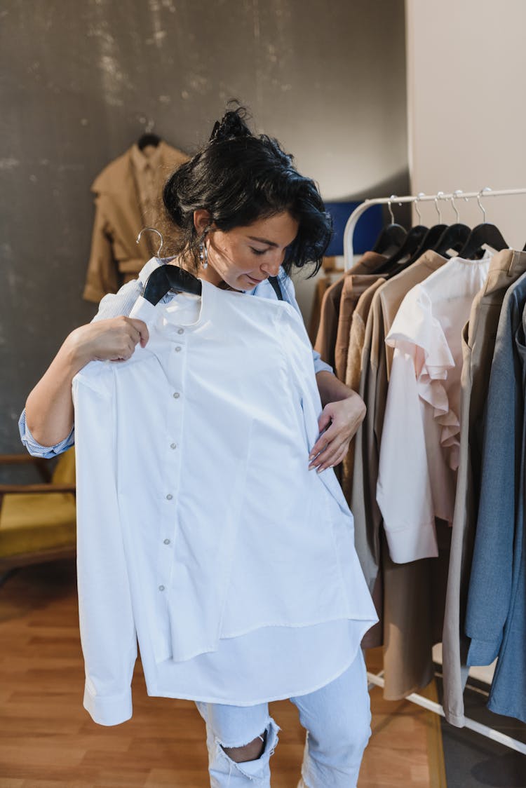 Woman Putting A White Shirt On A Hanger Against Her Body 