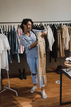 一名女子在一家时尚的精品店内浏览衣服，并查看架上的棕褐色裤子