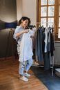 一名女子在光线充足、时尚的精品店里浏览衣架上的衣服
