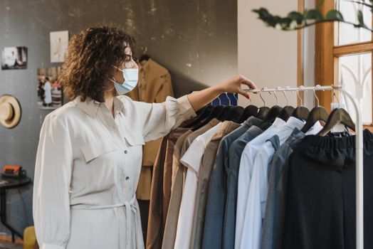 一名女子戴着口罩在精品店里挑选衣服
