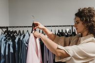 一名女子在精品店货架旁侧身浏览衣服