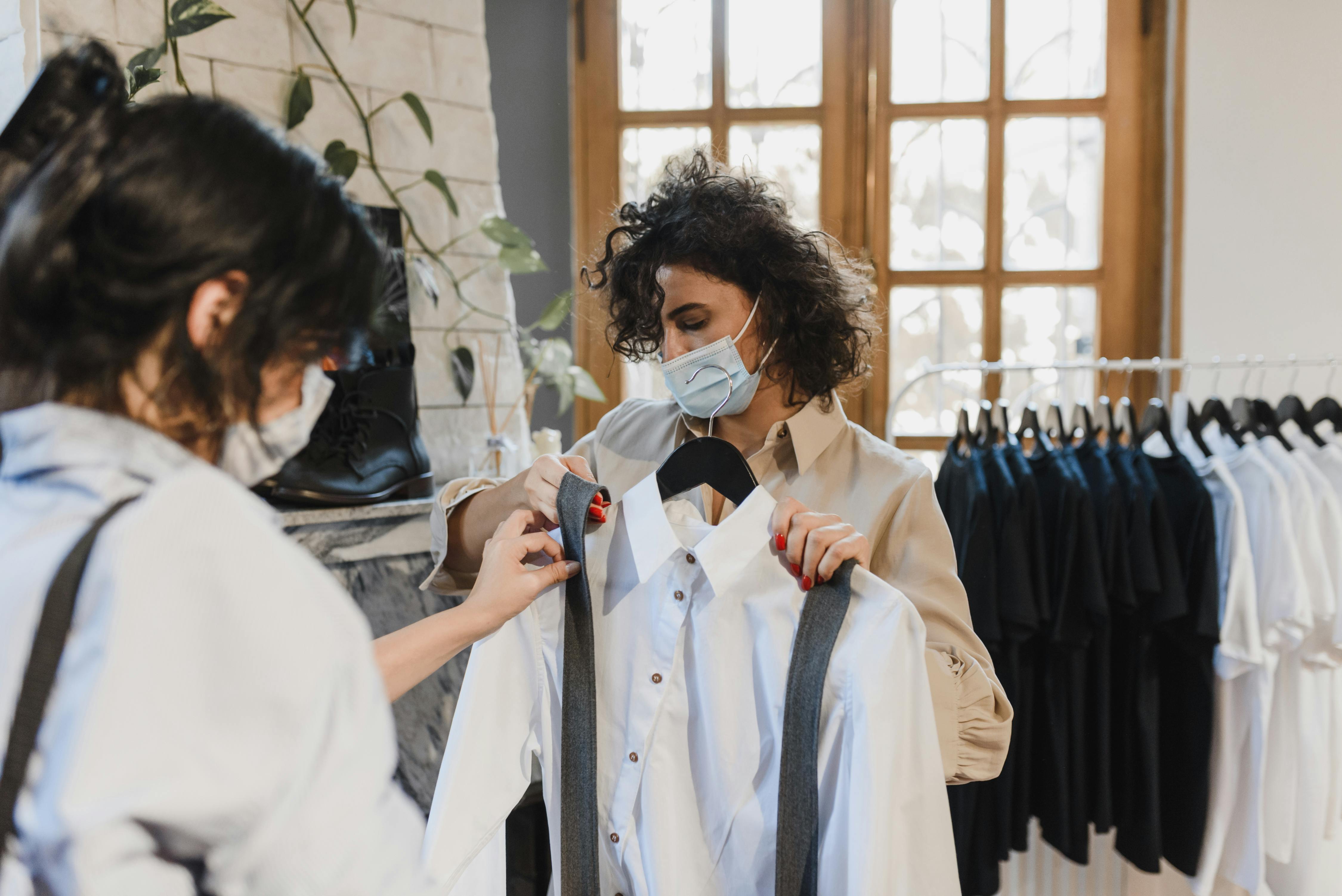 两名妇女戴着口罩在一家精品服装店购买衬衫